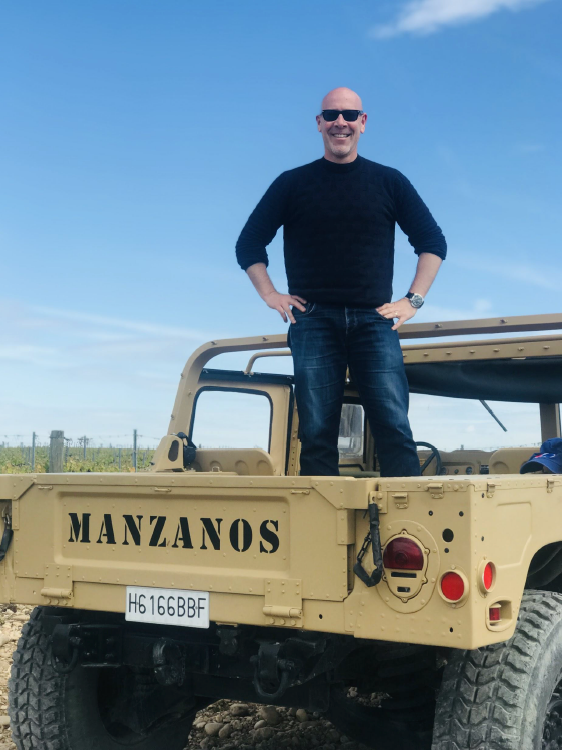 man standing in bed of pick up truck in wine country