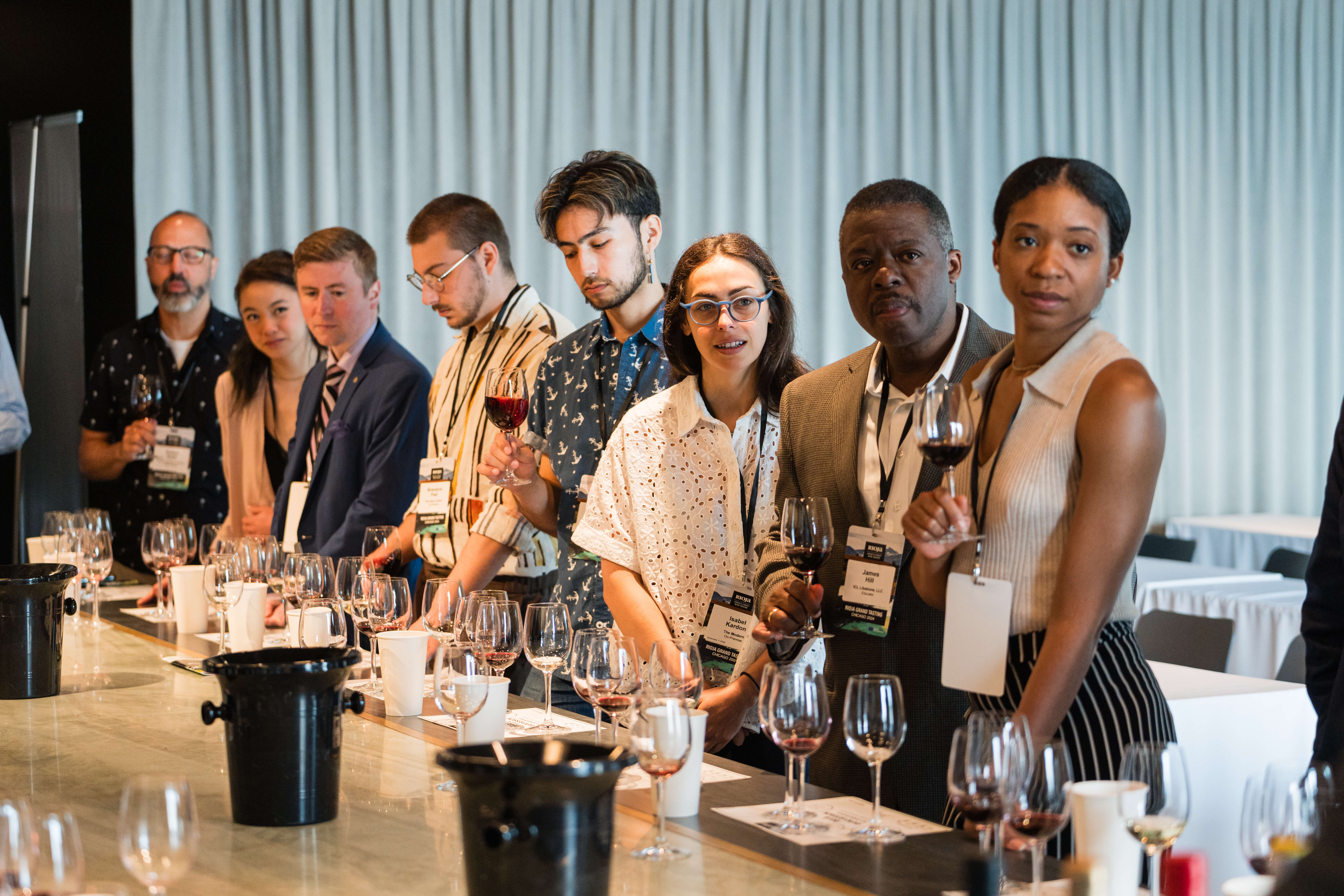 A group of people standing in front of a wine exhibit, learning about wine
